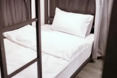 a bunk bed with white sheets and a pillow at 420 Hostel - Ekkamai Buds & Beds in Bangkok