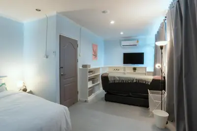 a bedroom with a bed and a couch and a television at 420 Hostel - Ekkamai Buds & Beds in Bangkok