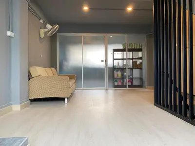 a living room with a couch and a glass door at Chiangmai vibe, City House, 7 mins to BTS, City center, Private room in Sathon, Private bathroom, Bangkok, Thailand in Bangkok