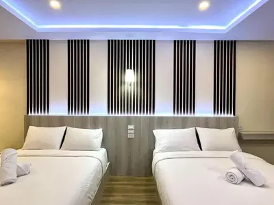 two beds with white pillows in a room at DiscoveryHome5 at Pratunammarket in Bangkok