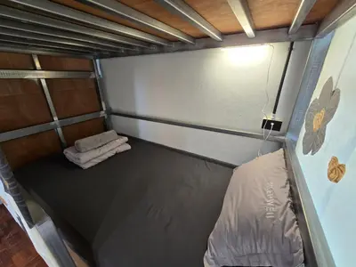 a small room with a bed and towels in it at Panda Lodge Home Stay in Bangkok
