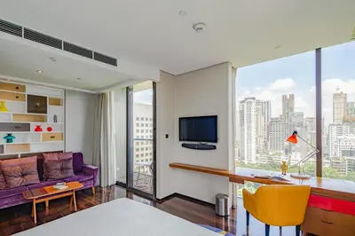 a living room with a purple couch and a large window at Hotel Indigo Bangkok Wireless Road by IHG in Bangkok