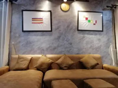 a brown couch in a living room with two pictures at The Lake Guest House in Ban Bang Phang