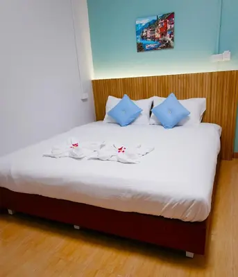 a bedroom with a bed with blue and white pillows at Fall Asleep hotel in Nonthaburi