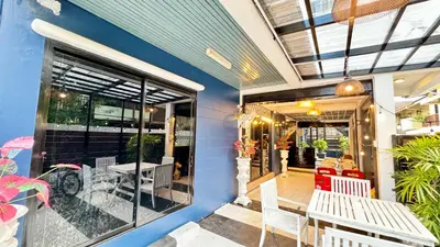 a patio with white tables and chairs and a window at FRIENDS@SaiLom in Bangkok
