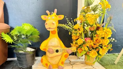a toy giraffe standing next to a vase of flowers at FRIENDS@SaiLom in Bangkok