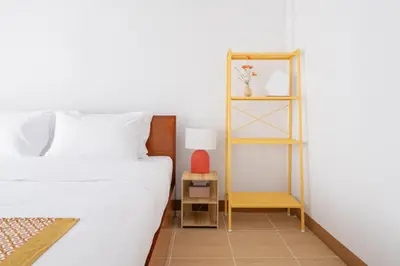 a bedroom with a white bed and a wooden shelf at Chummy House Khaosan 10-Min, Peace Haven in Bangkok