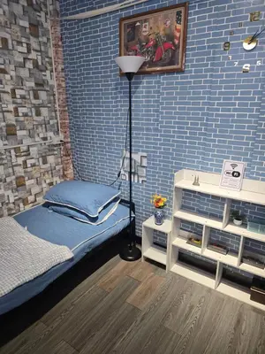 a room with a bed and a blue brick wall at 211 Spacious studio with breezy fan full amenities with free Wi-Fi in Bangkok