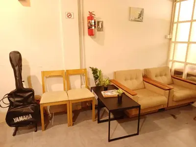 a living room with a couch and chairs and a guitar at Amsterdamned (อัมสเตอร์ดัมด์) in Bangkok