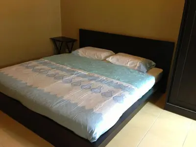 a bed with white sheets and two pillows at The State Apartment in Bangkok
