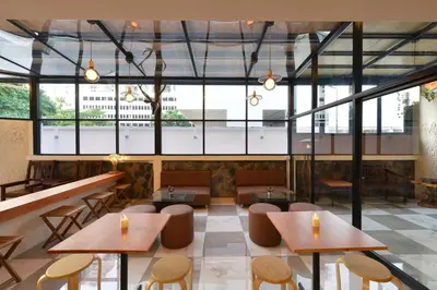 a restaurant with tables and chairs and large windows at Ratchathewi Hyde Away in Pratunam