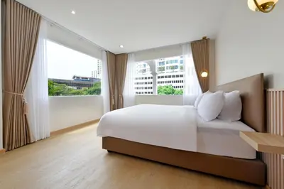 a bedroom with a bed and a large window at Ratchathewi Hyde Away in Pratunam