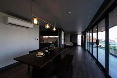 a kitchen and living room with a dining table and large windows at WE HOTEL RIVERFRONT in Bang Su