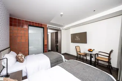 a hotel room with two beds and a table and chairs at WE HOTEL RIVERFRONT in Bang Su