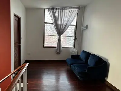 a living room with a blue couch and a window at Stay Tender in Bang Su