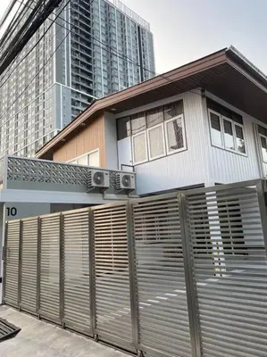 a house behind a fence in front of a building at Stay Tender in Bang Su