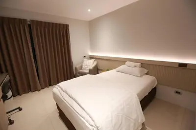 a bedroom with a white bed and a chair at BaanTip​ HomeStay in Amphoe Phra Khanong