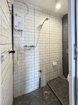 a bathroom with a shower with white tile walls at Chubby 9 Standard room in Ban Bang Phlat