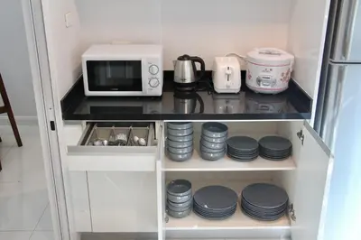 a cupboard with a microwave and some plates at Entire 3BR Townhome, Pool, Sukhumvit, BTS&MRT Asok in Bangkok