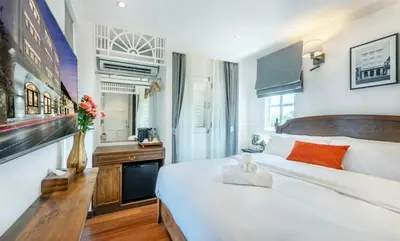 a bedroom with a large white bed and a vase with flowers at Cherie Bangkok Boutique Hotel in Bangkok