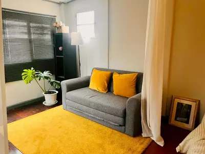 a living room with a gray couch with yellow pillows at MIDNIGHT CREPES Homecafe/Lifestyle Studio in Ban Bang Toei (1)