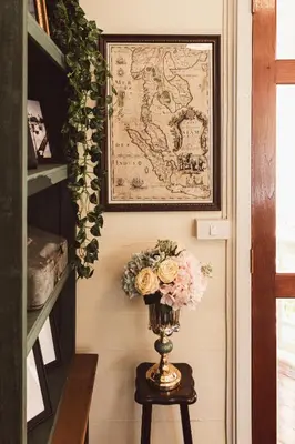 a vase with flowers on a table in a room at Wallaya Heritage Stay in Bangkok