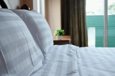 a bed with white pillows in a bedroom with a window at One Deves in Bangkok