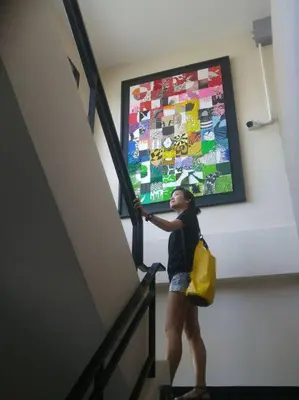 a woman is standing on a staircase with a painting on the wall at Mimi Cozy Apartment- Old town Siriraj Wanglang Market in Bangkok