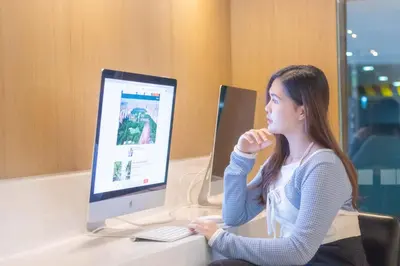 a woman sitting at a desk with a computer at Holiday Inn Express Bangkok Sukhumvit 11 by IHG in Bangkok