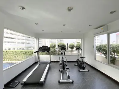 a gym with treadmills and ellipticals in a room with windows at Spacious 53 SQM - BTS Thong Lo - Ultra Fast WiFi in Khlong Toei