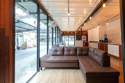 a living room with a brown couch in a building at My Cocoon Hostel แจ้งวัฒนะ in Nonthaburi