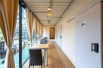 an office corridor with a long table and chairs at My Cocoon Hostel แจ้งวัฒนะ in Nonthaburi