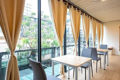 a room with tables and chairs and a large window at My Cocoon Hostel แจ้งวัฒนะ in Nonthaburi
