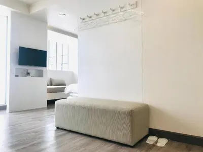 a white room with a ottoman in the middle of a bedroom at Urban house in Bangkok