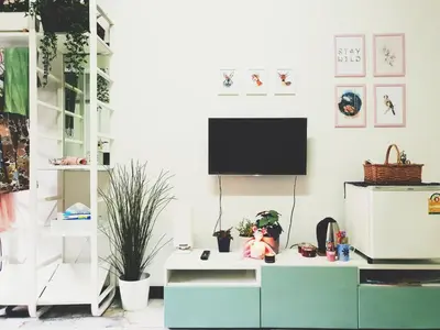 a living room with a tv on a white wall at Single Beds, Private Bath & Balcony, Shared Kitchen with Local Family by Pillows & Purrs in Bangkok