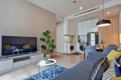 a living room with a blue couch and a kitchen at New 2-Bedroom Apartment in Asok in Bangkok
