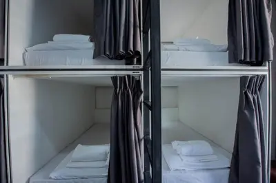 a room with three bunk beds and towels at Mascotte Hostel Silom in Bangkok