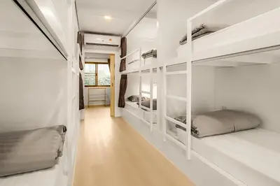 a room with white bunk beds and a hallway at The 63rd Hostel in Bangkok