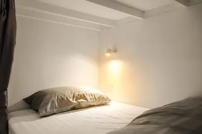 a bedroom with white walls and a bed with a pillow at The 63rd Hostel in Bangkok