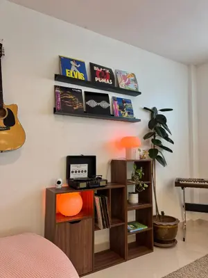 a room with a shelf with a tv and a guitar at Baan Farang in Bangkok