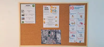 a cork bulletin board with posters on it at Baan Farang in Bangkok
