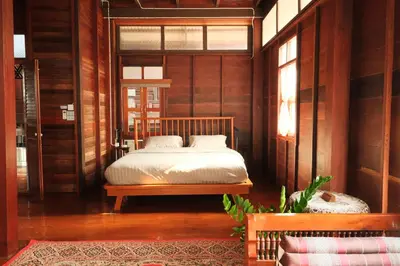 a bedroom with a bed in a room with wooden walls at Bannai Bangkoknoi บ้านในบางกอกน้อย in Ban Bang Bamru