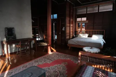 a bedroom with a bed and a table and a rug at Bannai Bangkoknoi บ้านในบางกอกน้อย in Ban Bang Bamru
