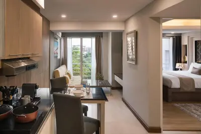 a room with a kitchen and a bedroom with a bed at Aspira Suites Sukhumvit 20 in Bangkok