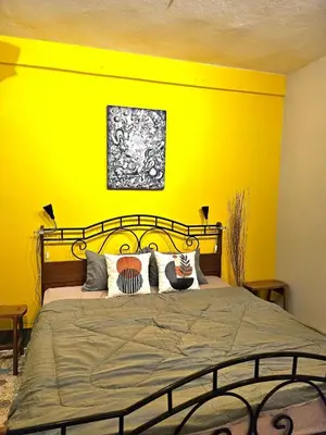 a bedroom with a large bed with a yellow wall at Cozy Gallery Studio at Chinatown in Bangkok