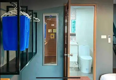 a bathroom with a toilet and a blue door at Purple House King BR Walk to Grand Palace in Bangkok