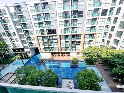 an apartment building with a swimming pool in front of it at คอนโด 1 ห้องนอน ใกล้บีทีเอสอ่อนนุช สายสีเขียว ที่นอนKing Size วิวสระว่ายน้ำ in Amphoe Phra Khanong
