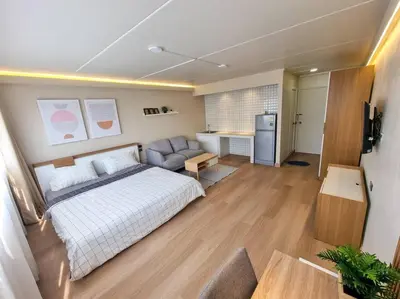 a bedroom with a bed and a couch and a refrigerator at BetterRoom เมืองทองธานี C6 in Pak Kret