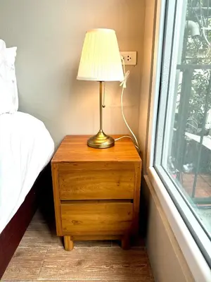 a lamp on a wooden night stand next to a window at Rimm49 Bangkok in Bangkok