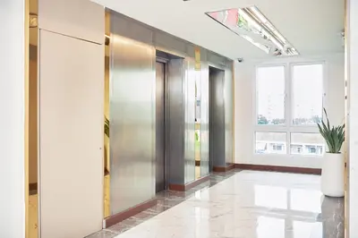 a hallway with elevators in a building with a window at Cozy Donmueang Hotel in Lak Si
